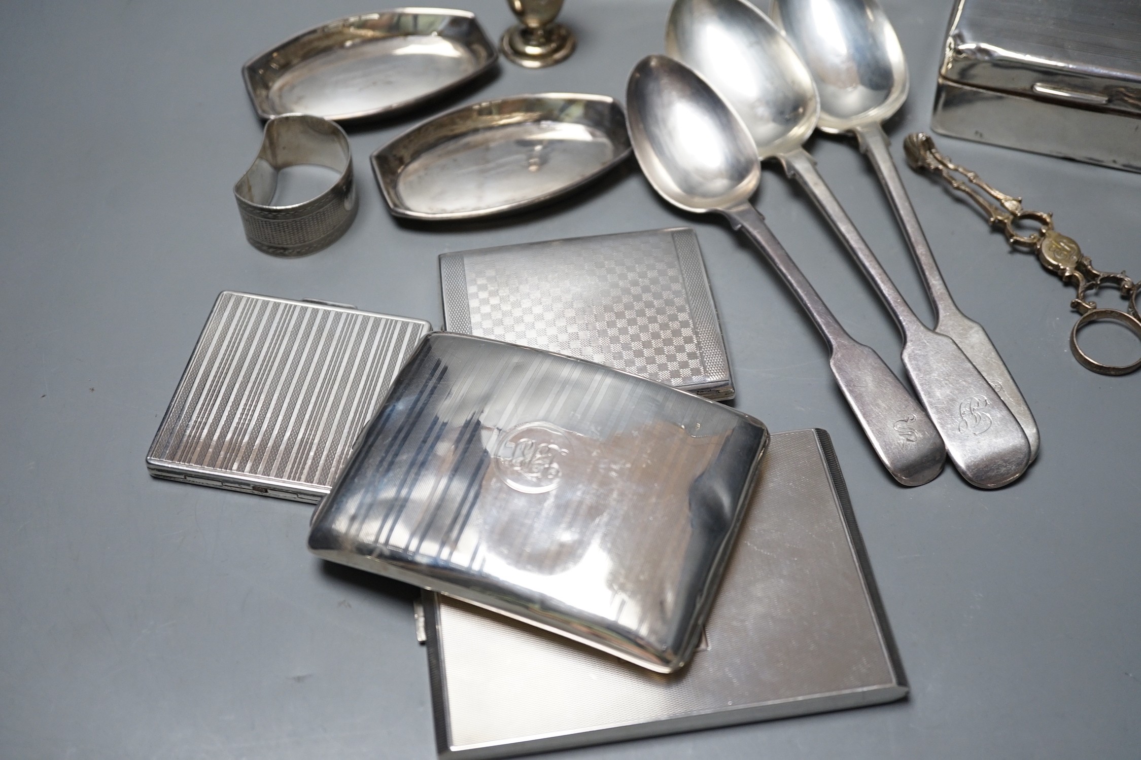 Mixed silver or white metal items including two cigarette boxes, three cigarette cases, cutlery, condiment and a napkin ring, gross